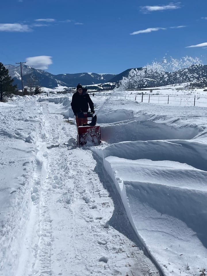 The author using a snowblower to unearth a road from snow drifts.