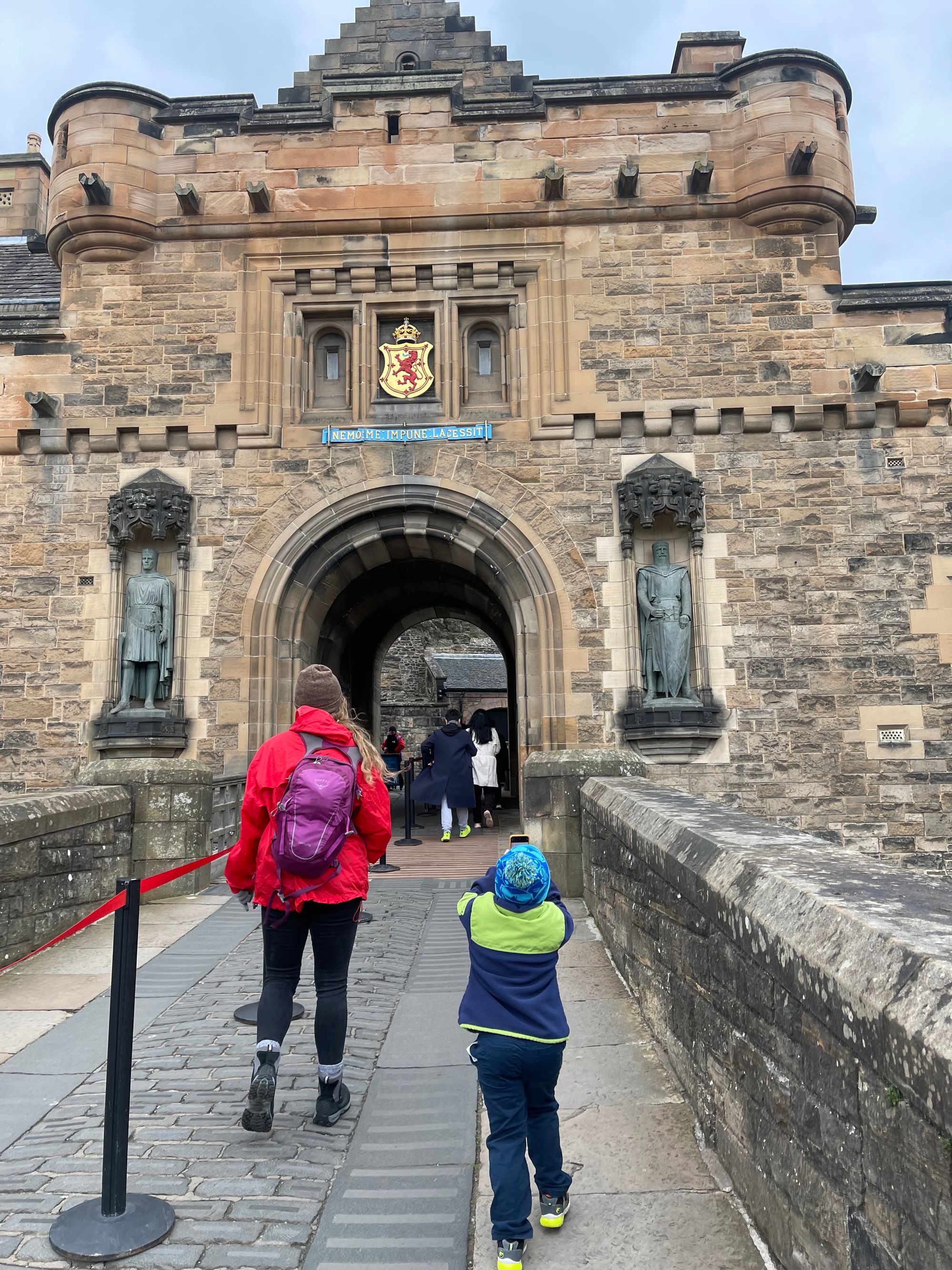 A woman and young boy look up at the entrance of Edinburgh Castle.