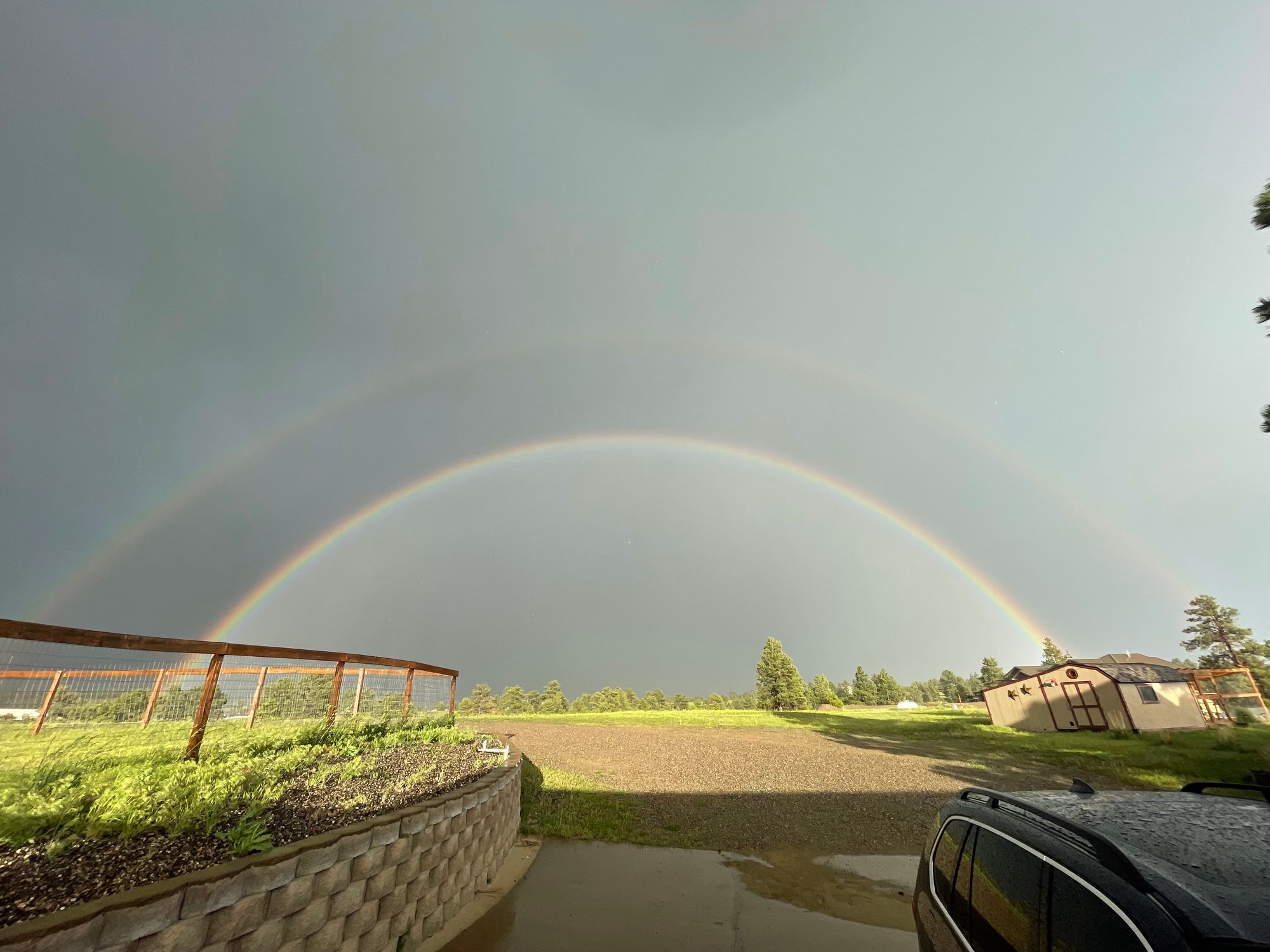 A double rainbow arches over a farm property